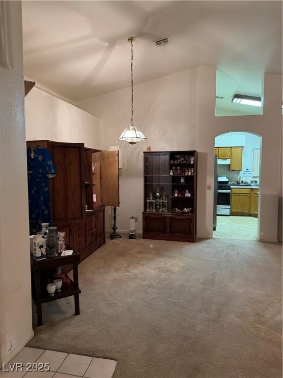 living room with arched walkways, light colored carpet, and a towering ceiling