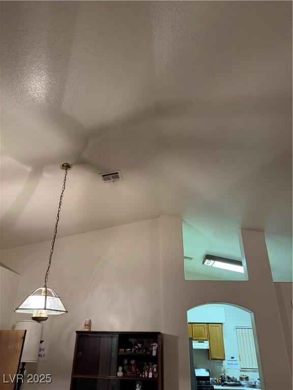 detailed view of arched walkways, stove, and under cabinet range hood