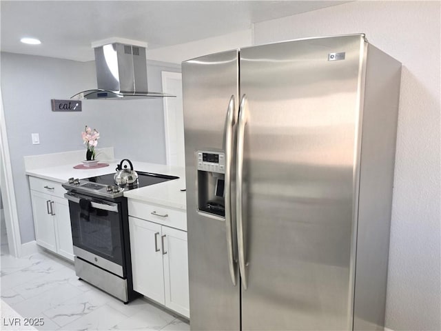 kitchen with light countertops, white cabinets, marble finish floor, stainless steel appliances, and wall chimney exhaust hood