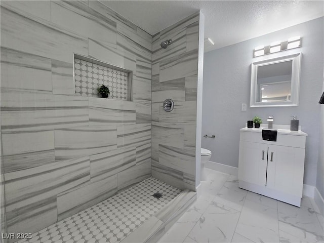 bathroom featuring baseboards, vanity, toilet, marble finish floor, and tiled shower