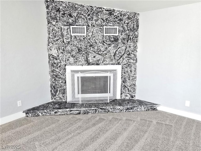 interior details with carpet, heating unit, a fireplace with raised hearth, and visible vents