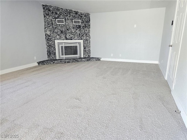 unfurnished living room with carpet flooring, baseboards, visible vents, and a stone fireplace