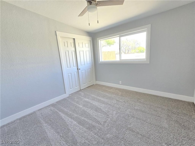 unfurnished bedroom featuring light colored carpet, baseboards, ceiling fan, and a closet
