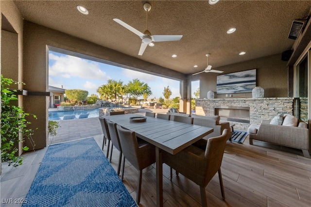 view of patio featuring an in ground hot tub, a ceiling fan, exterior kitchen, an outdoor pool, and outdoor dining space