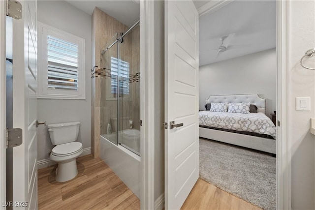 ensuite bathroom with ensuite bathroom, combined bath / shower with glass door, wood finished floors, and toilet