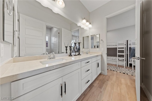 bathroom with a sink, double vanity, and wood finished floors