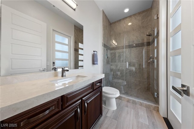 full bathroom with toilet, a stall shower, and vanity