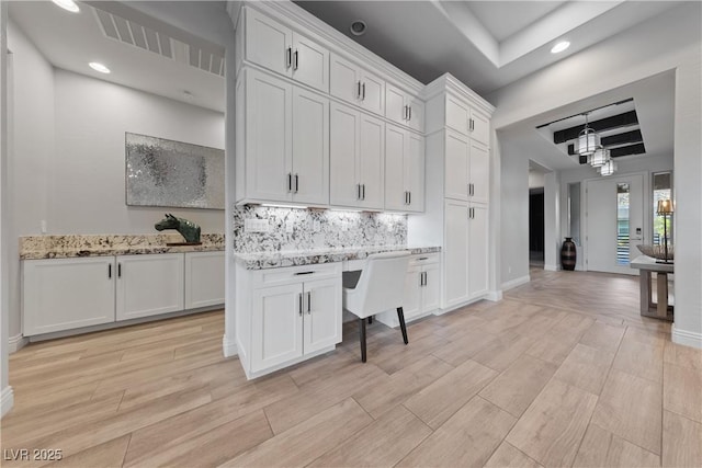kitchen with a raised ceiling, white cabinets, backsplash, and recessed lighting