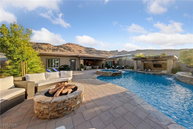 view of swimming pool with an outdoor living space with a fire pit, a patio area, a mountain view, and a pool with connected hot tub