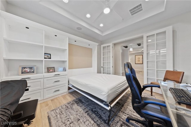 bedroom with french doors, visible vents, light wood-type flooring, a tray ceiling, and recessed lighting