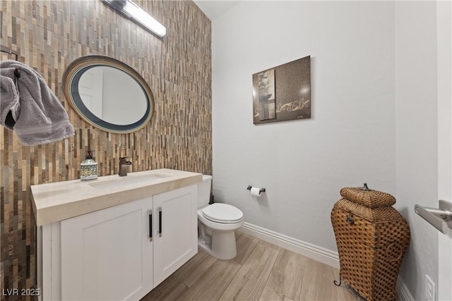 bathroom with baseboards, vanity, toilet, and wood finished floors