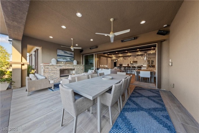 dining area featuring ceiling fan, a textured ceiling, wood finished floors, an outdoor stone fireplace, and recessed lighting