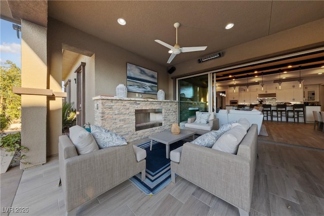 living room with recessed lighting, ceiling fan, wood finished floors, and an outdoor stone fireplace