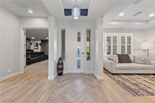 foyer featuring parquet floors, a tray ceiling, visible vents, and baseboards
