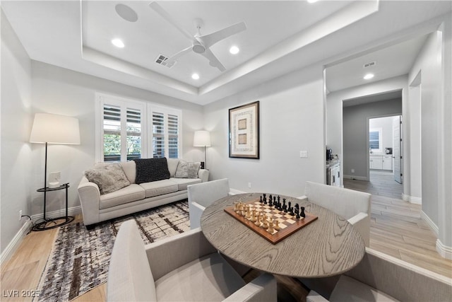 living room with baseboards, a ceiling fan, wood finished floors, and visible vents