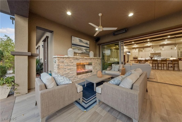 exterior space featuring a ceiling fan and an outdoor living space with a fireplace