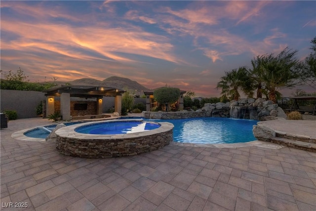 pool at dusk featuring a gazebo, a pool with connected hot tub, and a patio area