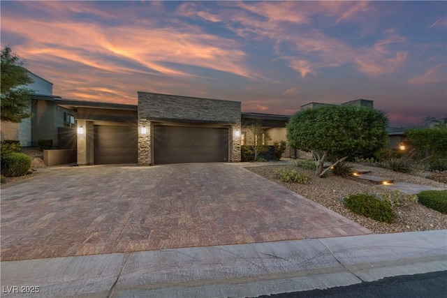 view of front of house with an attached garage, decorative driveway, and stone siding