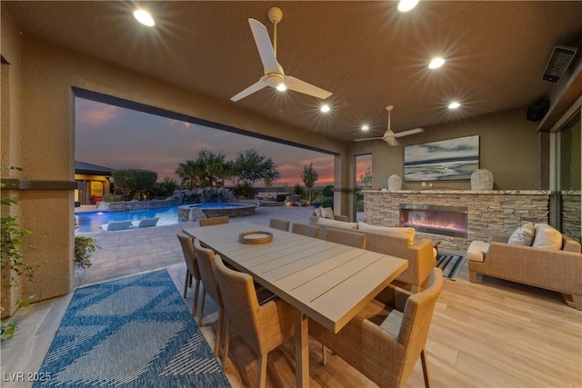 exterior space with an outdoor stone fireplace, recessed lighting, a ceiling fan, wood finished floors, and visible vents