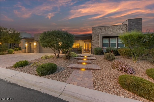 view of front of property with a garage, an outdoor fire pit, driveway, and stone siding