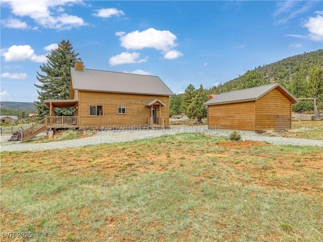 exterior space with a yard, metal roof, a mountain view, and a chimney