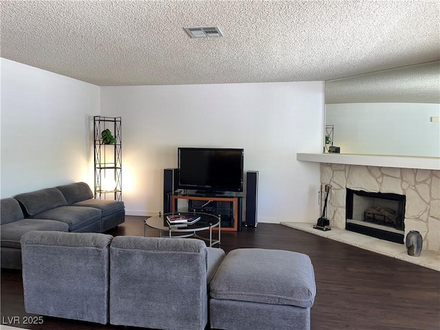 living room with visible vents, a textured ceiling, wood finished floors, and a fireplace