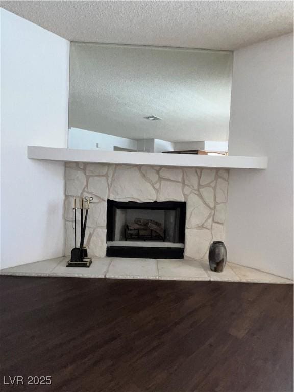 interior details featuring a textured ceiling, wood finished floors, and a fireplace