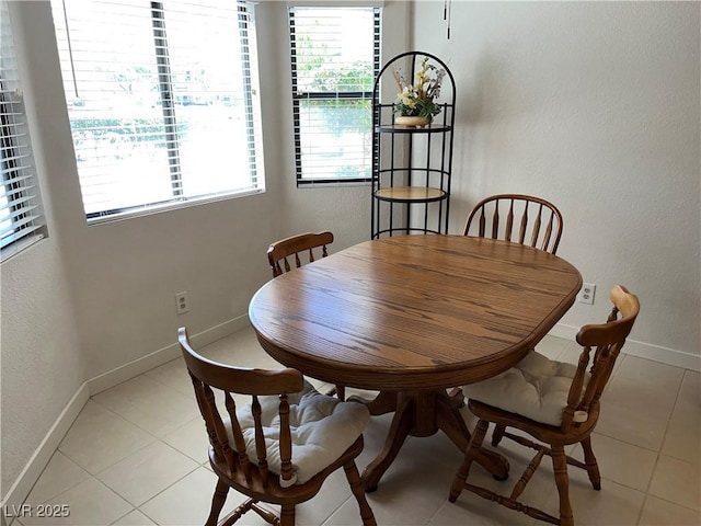 dining space with light tile patterned flooring, baseboards, a textured wall, and a healthy amount of sunlight