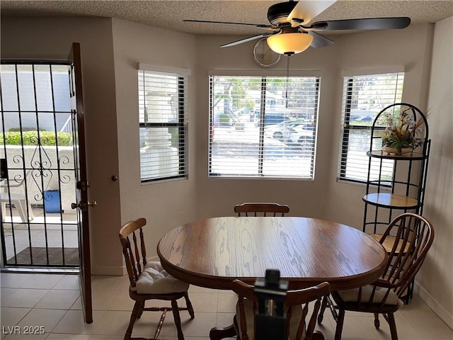 dining room with a ceiling fan, baseboards, light tile patterned floors, and a healthy amount of sunlight