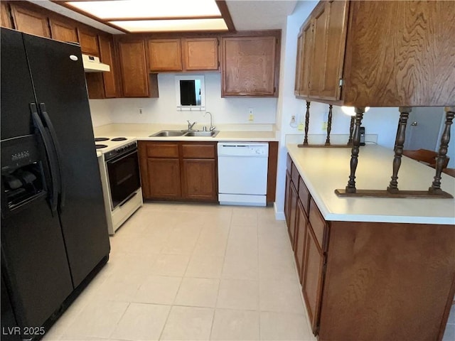 kitchen with a sink, brown cabinets, white appliances, and light countertops