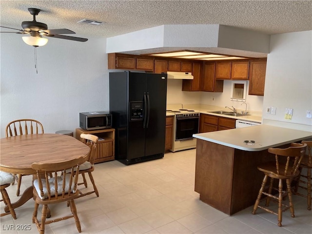 2704 Otter Creek Ct Unit 101, Las Vegas, NV 89117 - kitchen featuring white range with electric cooktop, black fridge, stainless steel microwave, under cabinet range hood, and a peninsula