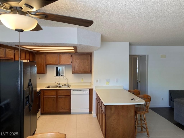2704 Otter Creek Ct Unit 101, Las Vegas, NV 89117 - kitchen with black appliances, a peninsula, a breakfast bar, a sink, and light countertops