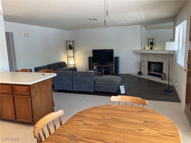 2704 Otter Creek Ct Unit 101, Las Vegas, NV 89117 - dining area featuring light tile patterned floors, a stone fireplace, and a textured ceiling