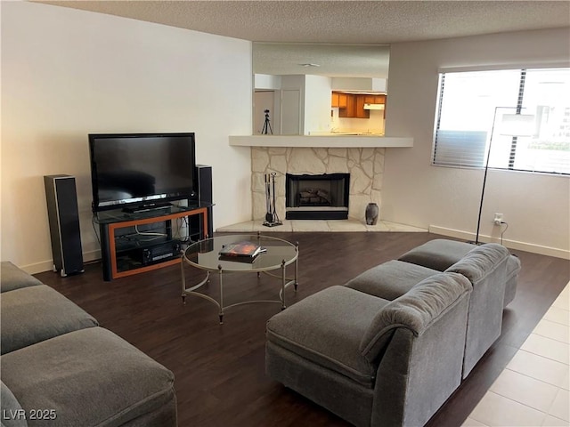 2704 Otter Creek Ct Unit 101, Las Vegas, NV 89117 - living room with wood finished floors, a stone fireplace, baseboards, and a textured ceiling