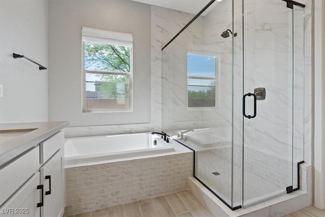 full bath featuring vanity, a marble finish shower, a bath, and wood finished floors