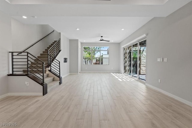 unfurnished living room featuring baseboards, a ceiling fan, stairs, and wood finished floors