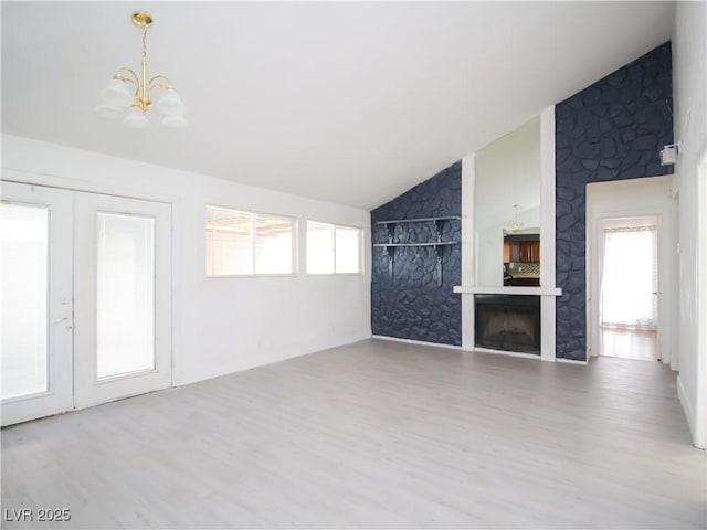 unfurnished living room featuring an inviting chandelier, a wealth of natural light, wood finished floors, and lofted ceiling