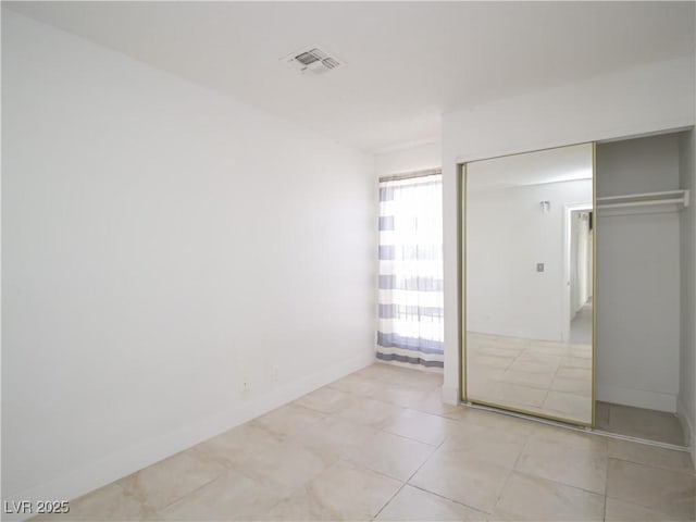 unfurnished bedroom with baseboards, tile patterned flooring, a closet, and visible vents