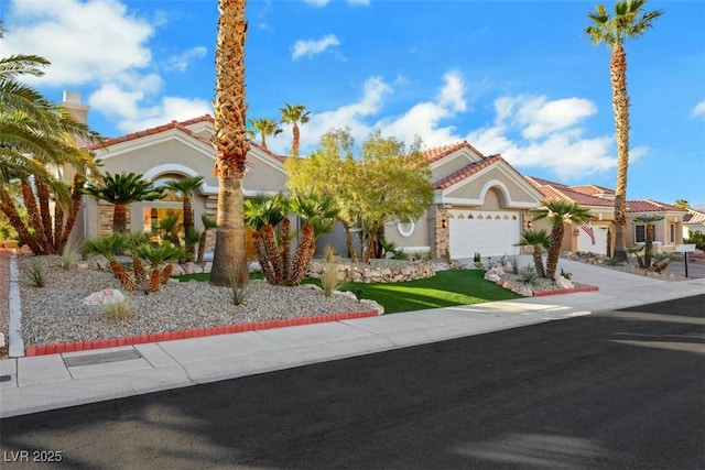 mediterranean / spanish house with a garage, stucco siding, driveway, and a tile roof