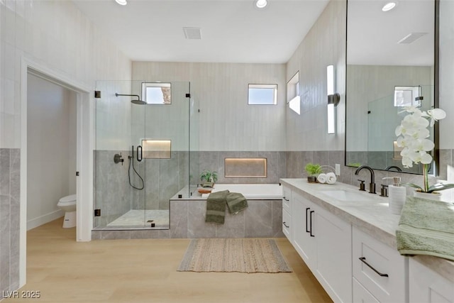 bathroom with vanity, toilet, a shower stall, wood finished floors, and a garden tub