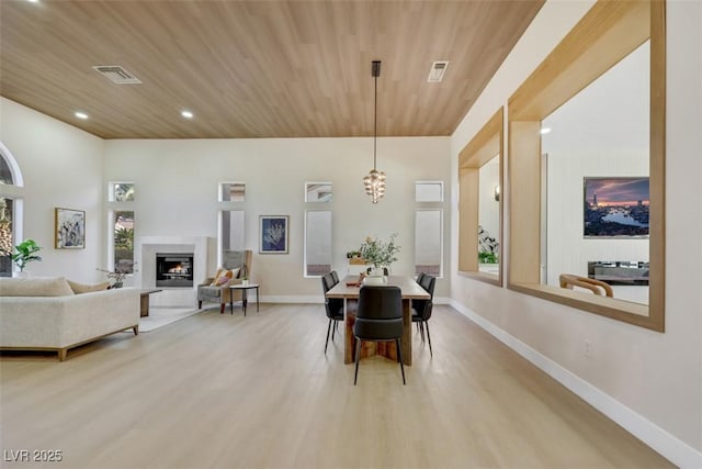 dining space featuring a glass covered fireplace, wood finished floors, baseboards, recessed lighting, and wood ceiling