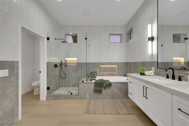 full bathroom featuring a bath, a stall shower, toilet, and tile walls