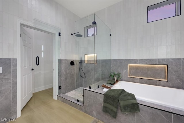 full bath featuring tile walls, a garden tub, and a stall shower