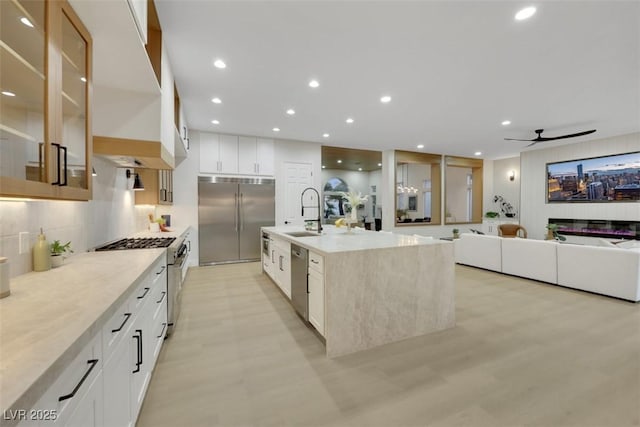 kitchen featuring decorative backsplash, a ceiling fan, high end appliances, a sink, and recessed lighting
