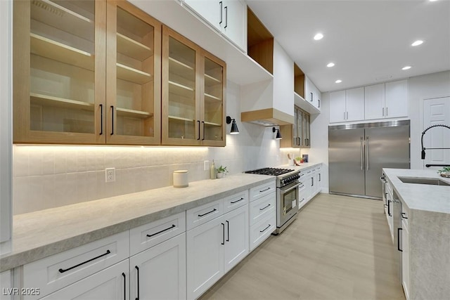 kitchen featuring open shelves, high end appliances, glass insert cabinets, and tasteful backsplash