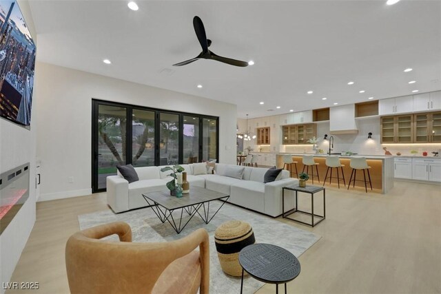 living area featuring ceiling fan, a fireplace, baseboards, light wood finished floors, and recessed lighting