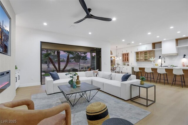 living room with a glass covered fireplace, ceiling fan, and recessed lighting