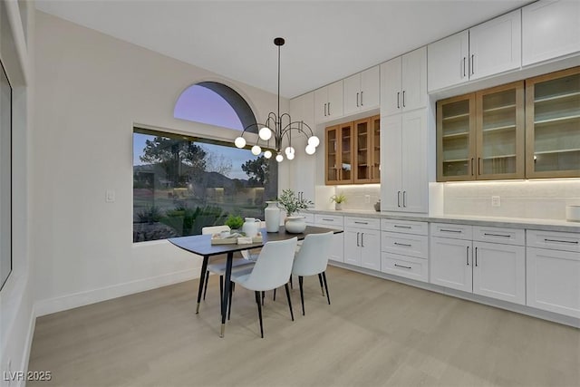 dining area featuring baseboards, an inviting chandelier, and light wood-type flooring