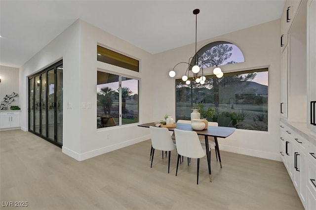 dining space with baseboards, a chandelier, plenty of natural light, and light wood-style floors