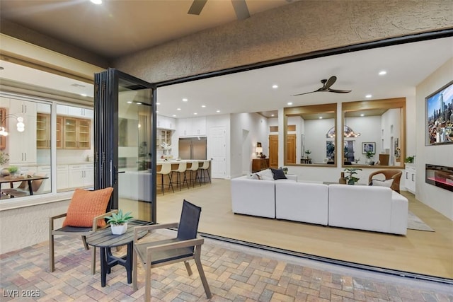 living area featuring recessed lighting, a ceiling fan, and brick floor